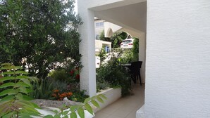 An outdoor patio with a white wall, a black chair, and a white spherical object.