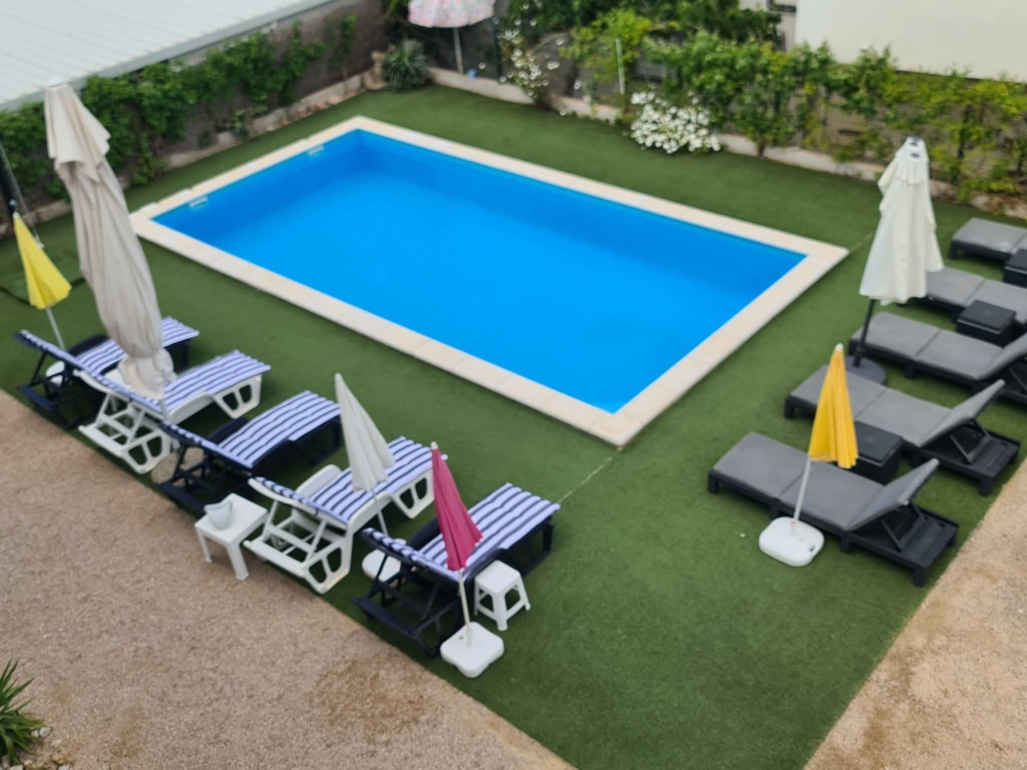 A rectangular pool with lounge chairs and umbrellas.