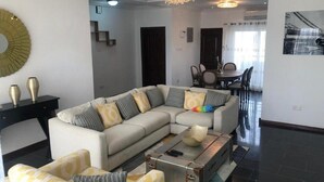 Una sala de estar moderna con un sofá modular, una mesa de centro y un comedor con una mesa y sillas.
