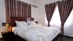 Una cama bien hecha con ropa de cama floral, un cabecero de madera y dos lámparas de noche.