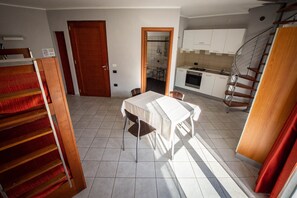 A compact living space with a dining area, kitchen, and a staircase leading to an upper level.