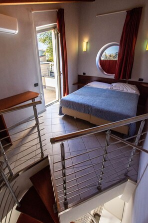 A bedroom with a bed, a window, and a staircase.