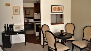 A compact kitchen with a microwave, a small refrigerator, and a dining area with a table and four chairs. - A Perfect Retreat in Grand Forks (Grand Forks)