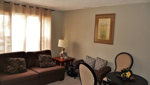 A living room with a sofa, armchair, table, lamp, and a framed picture on the wall. - A Perfect Retreat in Grand Forks (Grand Forks)