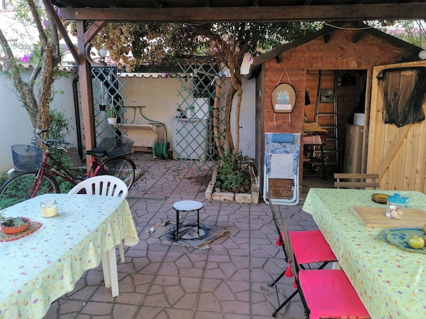 A patio area with tables and chairs, a bicycle, and a wooden structure.