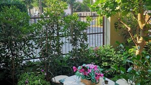 A patio with a table and chairs, surrounded by lush greenery and a metal fence. - Room in Apartment - Villa Piera Holiday Home in Cremona Apartment With Independent Entrance (Cremona)