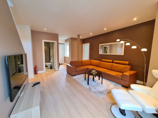 A modern living room with a sectional sofa, a flat-screen TV, and a floor lamp.