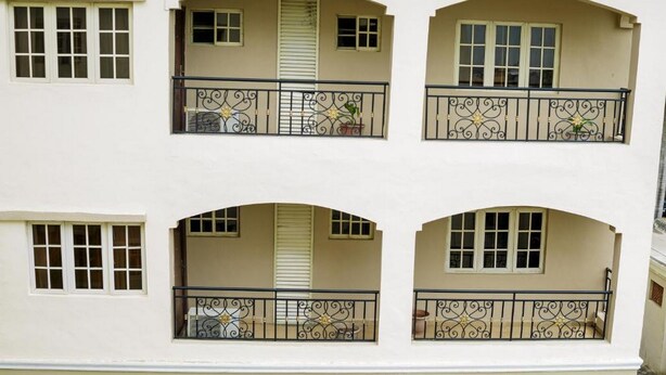 Een gebouw met vier balkons, elk voorzien van een sierhekwerk en een raam.
