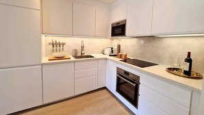 A modern kitchen with white cabinetry, a built-in oven, a microwave, and a coffee machine. - Bright And Modern Apartment Near Center, 85 M2, Fully Equipped, Free Parking (Stavanger)