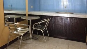 A small kitchen area with two metal chairs, a round table, and a countertop with a sink. - Reddoorz Plus Near Municipality of Luisiana Laguna (Luisiana)