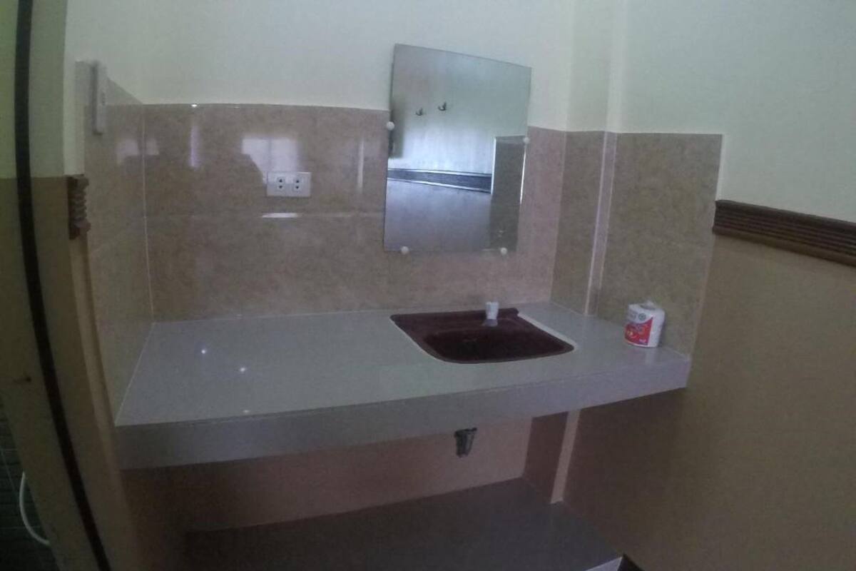 A bathroom with a sink, mirror, and a small trash bin.
