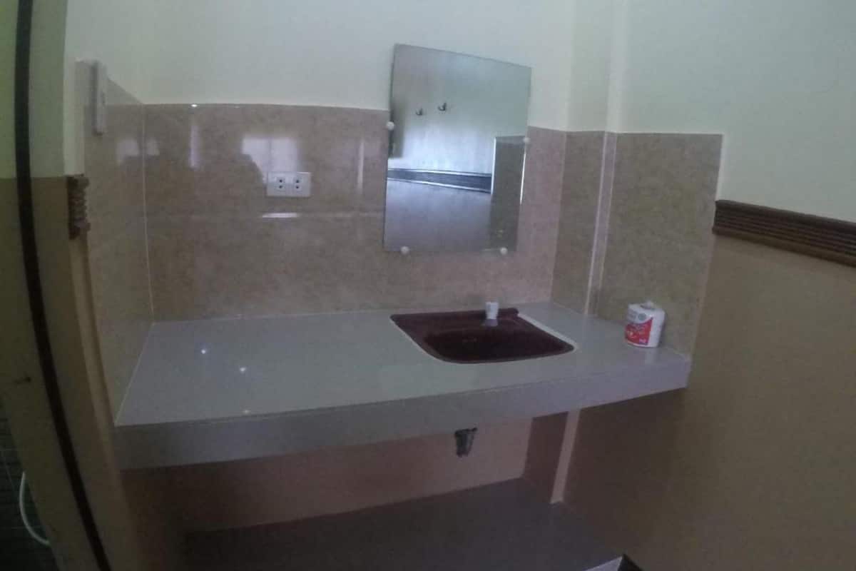 A bathroom with a sink, mirror, and a small trash bin.