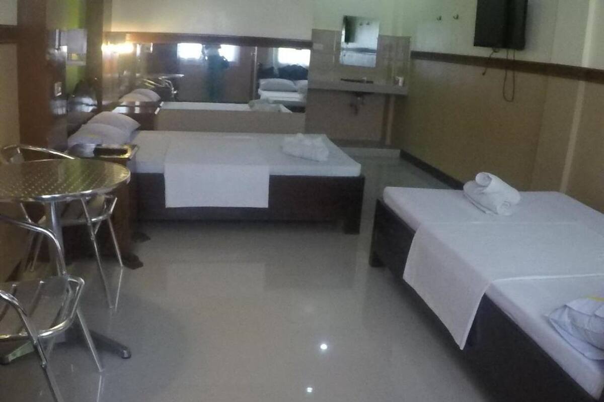 A hotel room with a bed, a small table, a chair, and a mirror.