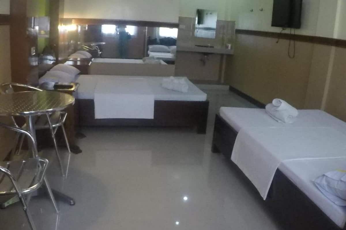 A hotel room with a bed, a small table, a chair, and a mirror.