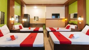 A hotel room with two beds, each with red and white bedding, a flat-screen TV mounted on the wall, and a mirror above the bed. - Reddoorz Plus near Municipality of Luisiana Laguna (Luisiana)
