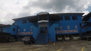 A blue building with the sign "Luisana Travellers Inn" on the front. There are stairs leading up to the entrance, and a parking area in front. - Reddoorz Plus Near Municipality of Luisiana Laguna (Luisiana)