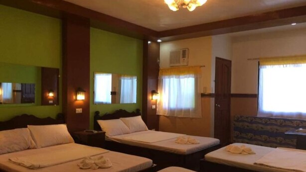 A hotel room with three beds, each with towels, a large mirror, and a chandelier. - Reddoorz Plus Near Municipality of Luisiana Laguna (Luisiana)