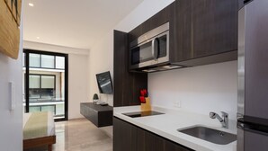 A modern kitchen with dark cabinetry, a white countertop, a built-in microwave, and a stainless steel sink. - Cozy Studio In Playa Del Carmen Downtown - Few Steps From the Beach!!! (Playa del Carmen)