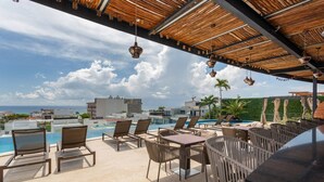 A rooftop pool area with lounge chairs and a bar, overlooking a cityscape and the ocean. - Cozy Studio In Playa Del Carmen Downtown - Few Steps From the Beach!!! (Playa del Carmen)