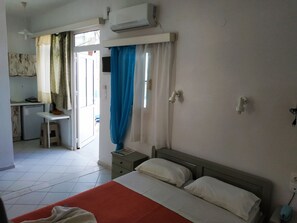 A room with a bed, a desk, a chair, an air conditioning unit, and a window with curtains. - A Studio With Balcony (Malevizi)