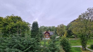 Un grand bâtiment de style traditionnel, entouré d’une végétation luxuriante et d’arbres.