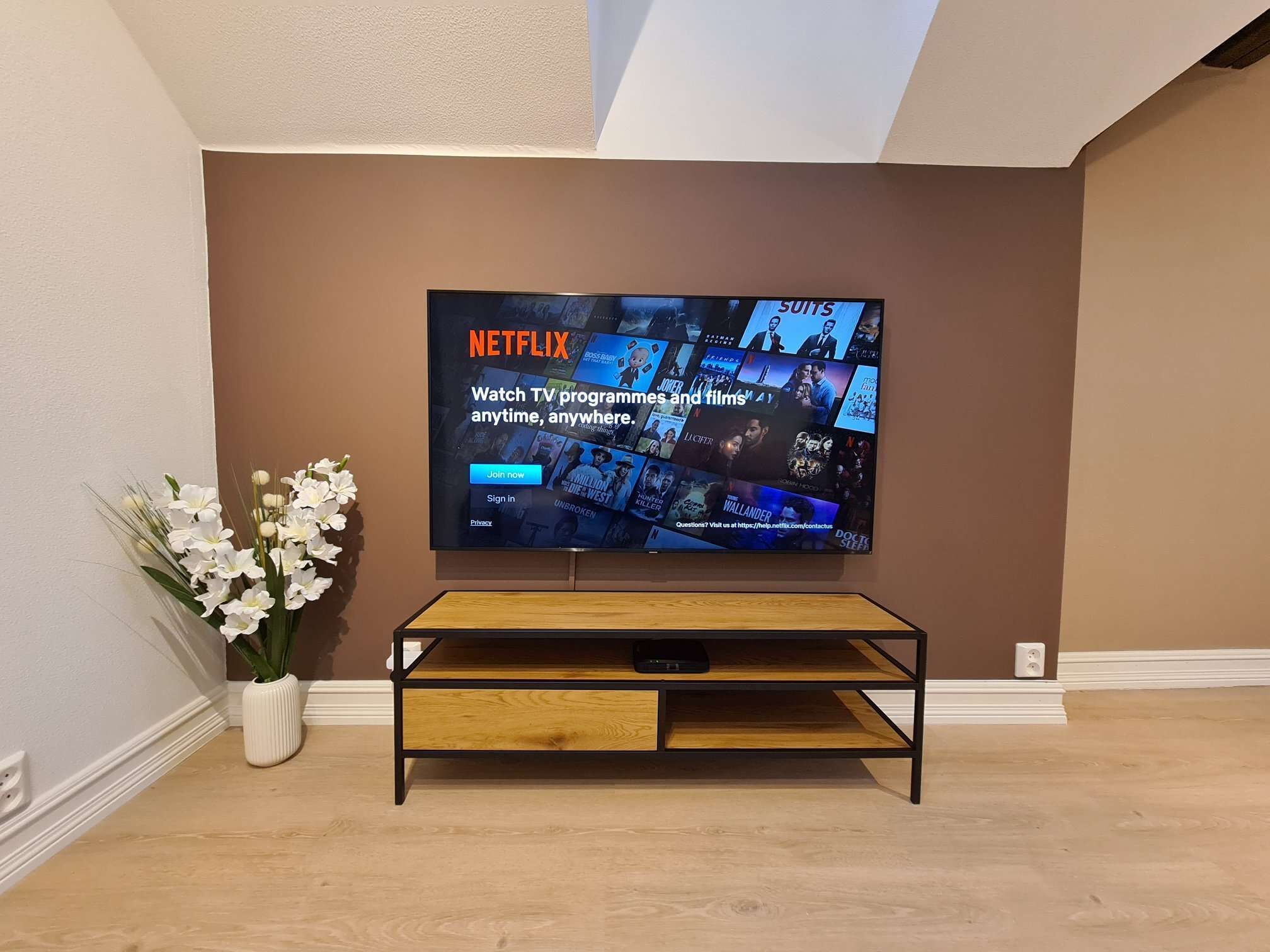 A flat-screen TV mounted on a wall displaying the Netflix interface.