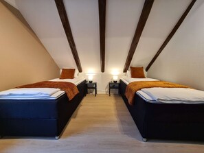 A twin bedroom with two beds, wooden beams on the ceiling, and bedside tables with lamps. - Beautiful Penthouse Near Center, 2-bedroom, Balcony and Free Parking (Stavanger)