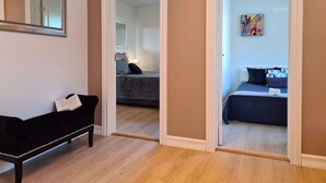A room with a black sofa, a bed with a blue bedspread, and a painting on the wall. - Bright And Modern - 2-bedroom, Central, Free Parking (Stavanger)