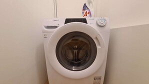Een witte wasmachine met bedieningspaneel en een zeepbakje bovenop.