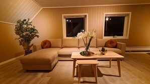 A cozy living room with a sectional sofa, a coffee table, and a potted plant.