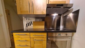 A kitchen with wooden cabinets, a stainless steel oven, and a black countertop.