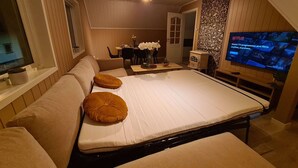 A bedroom with a large bed, a TV, and a dining area with a table and chairs.