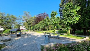 Een park met picknicktafels, een prieel en een grindpad.