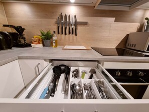 A kitchen with a drawer organizer containing utensils, a coffee maker, and a plant on the counter. - Room-deluxe Room 4 Rent, King-size Bed, (Stavanger)