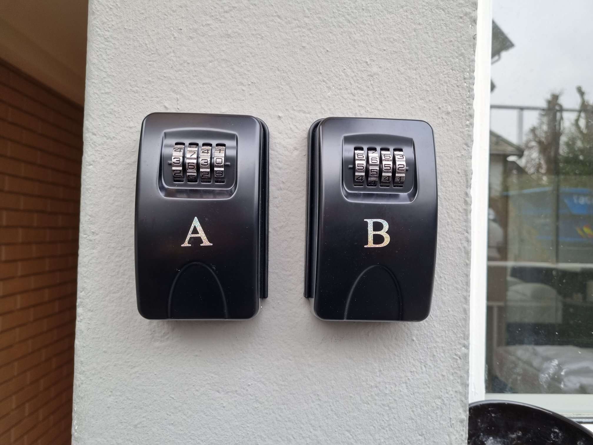 Deux interphones noirs, portant les lettres A et B, sont fixés sur un mur blanc.