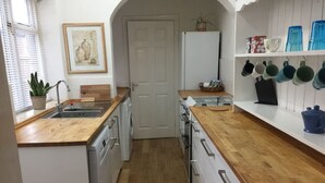 A compact kitchen with wooden countertops, a built-in dishwasher, a refrigerator, and a door leading to another room. - Cosy Cottage Sleeps 6 Suit Families, Contractors, Couples (Chesterfield)