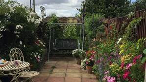 A garden patio with a metal table and chairs, surrounded by various potted plants and flowers. - Cosy Cottage Sleeps 6 Suit Families, Contractors, Couples (Chesterfield)