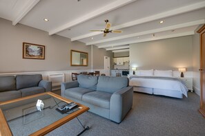 A hotel room with a large bed, a sofa, a coffee table, and a dining area. - Manata Homestead and Lodge (Otago)