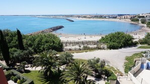 Une zone côtière avec une plage, une digue rocheuse, du sable et une végétation luxuriante.