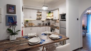 Una cocina moderna con armarios blancos, una mesa de comedor de madera para cuatro personas y una lámpara colgante.