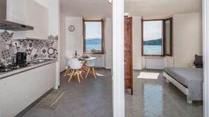 Een kleine keuken met een eethoek, een bed en uitzicht op zee.