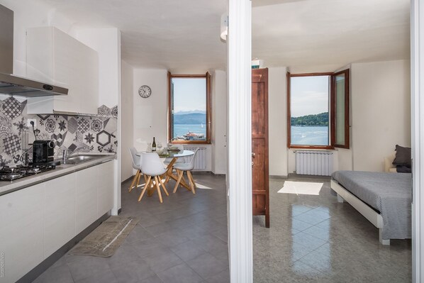 A compact kitchen with a dining area, a view of the sea, and a bed.