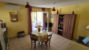 Un área de comedor con una mesa, sillas, una estantería y un sofá.