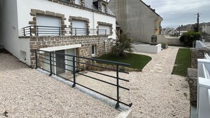 Un edificio de paredes de piedra y blanco, camino de grava y un pequeño césped.