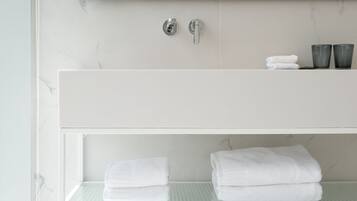 Une salle de bain moderne avec un meuble-lavabo blanc, un pare-feu en marbre et un grand miroir.