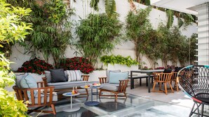 Eine moderne Außenpatio mit Glastisch, Holzstühlen und einer Couch.