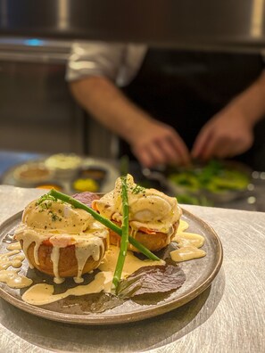 A plate of food with a creamy sauce and green garnish, with a chef in the background.