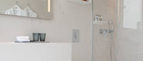 Un baño moderno con ducha de vidrio, tocador blanco con espejo y un inodoro.