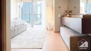 Een moderne hotelkamer met een groot bed, een bank, een flatscreen televisie en uitzicht op de stad door middel van kamerhoge ramen.