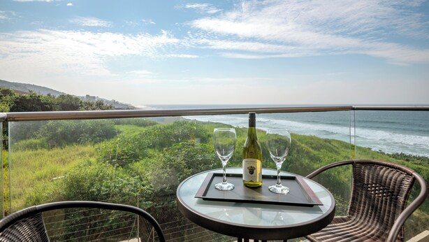 A balcony with a table, two wine glasses, and a bottle of wine. - Sea De La Vie 25 (La Mercy)